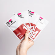 Hand holding 'The Edge' skincare product packages on a light gray background